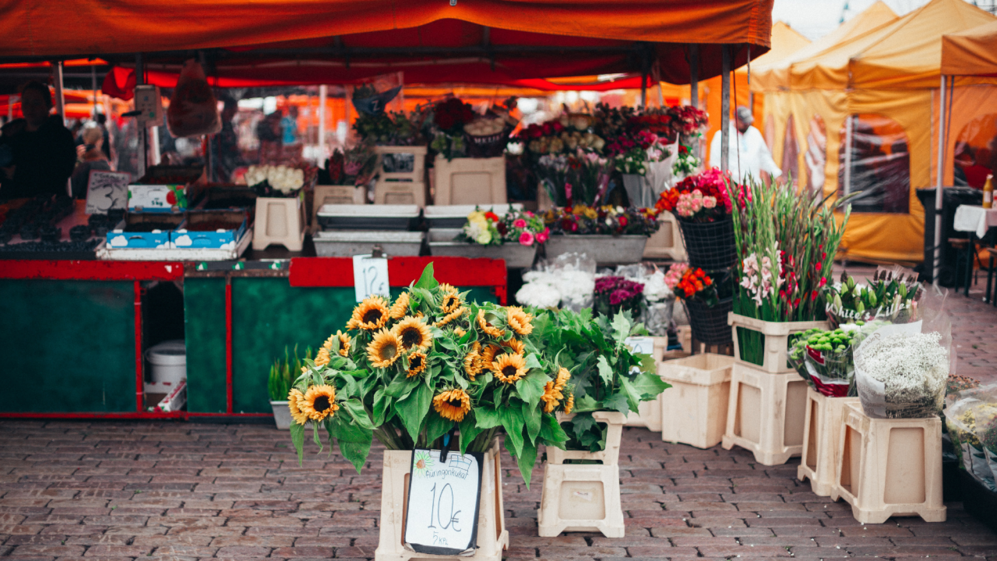 An image of a local farmers market, selling fresh flowers, organic fruit, locally grown vegetables and goods. for the Earthed blog post what is localisation.